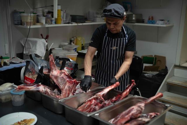 A cook from Thailand prepares reindeer legs in the kitchen of the Nuka cafй in Ilulissat, Greenland, on March 19, 2026. Around 1,200 Filipinos are settled in Greenland, which has 57,000 inhabitants, making them the largest foreign diaspora in this Danish territory. According to Greenland’s employers’ organisations, 5 to 6% of workers in the Arctic territory are now Asian, drawn by expanding sectors such as tourism. (Photo by Florent VERGNES / AFP)