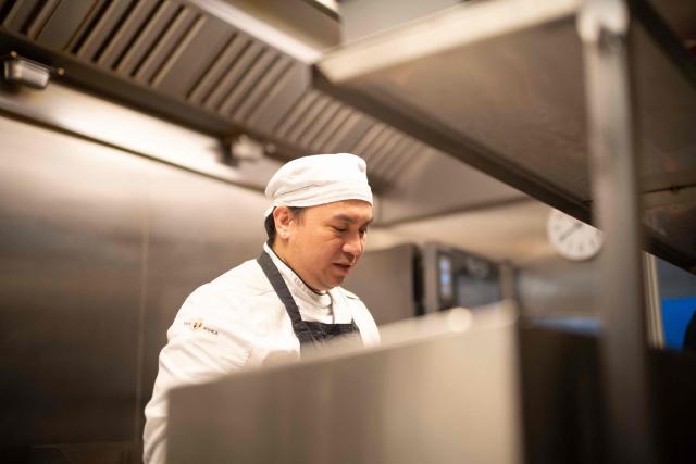 Owie Garciano, a Philippines cook, stands behind a stove in the cafй Nuka, in Ilulissat, Greenland, on March 19, 2026. Around 1,200 Filipinos are settled in Greenland, which has 57,000 inhabitants, making them the largest foreign diaspora in this Danish territory. According to Greenland’s employers’ organisations, 5 to 6% of workers in the Arctic territory are now Asian, drawn by expanding sectors such as tourism. (Photo by Florent VERGNES / AFP)