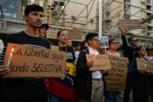 A young man holds a sign that reads in Spanish: "Freedom remains selective," during a vigil called by relatives of political prisoners in Caracas on May 22, 2026. Venezuela's interim president, Delcy Rodrнguez, said on May 22 that the release of political prisoners will exceed 500 “in the coming hours,” as she announced during an official broadcast. (Photo by Maryorin Mendez / AFP)