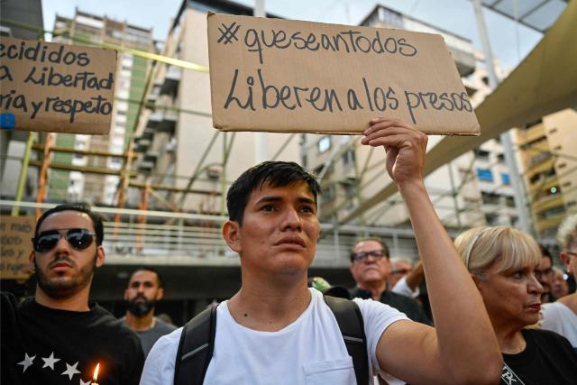 A young man holds a sign that reads in Spanish: "Release the prisoners," during a vigil called by relatives of political prisoners in Caracas on May 22, 2026. Venezuela's interim president, Delcy Rodrнguez, said on May 22 that the release of political prisoners will exceed 500 “in the coming hours,” as she announced during an official broadcast. (Photo by Maryorin Mendez / AFP)