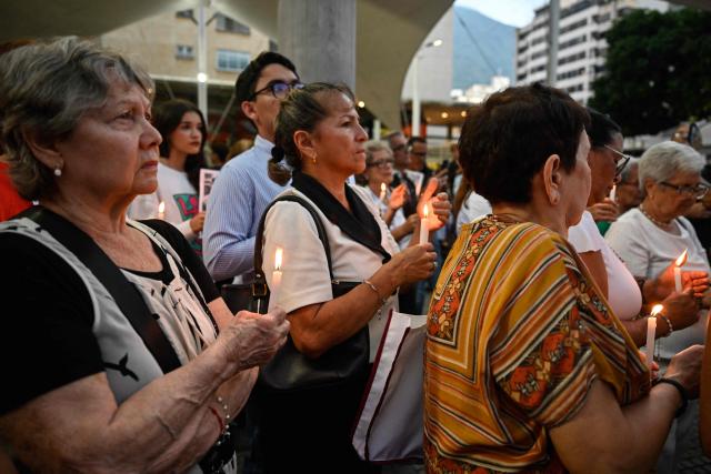 Relatives of political prisoners hold candles during a vigil in Caracas on May 22, 2026. Venezuela's interim president, Delcy Rodrнguez, said on May 22 that the release of political prisoners will exceed 500 “in the coming hours,” as she announced during an official broadcast. (Photo by Maryorin Mendez / AFP)