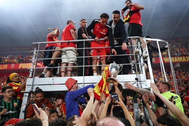 Lens' French forward #10 Florian Thauvin and Lens' French head coach Pierre Sage reach for the French Cup trophy during a celebration after Lens RC won the French Cup final football match against Nice OGC in Lens, northern France, on May 22, 2026. (Photo by FRANCK FIFE / AFP)