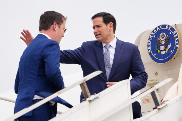 US Secretary of State Marco Rubio (R) waves as he boards his plane for New Delhi with the US Ambassador to India Sergio Gor at Netaji Subhash Chandra Bose International Airport in Kolkata on May 23, 2026. Rubio arrived May 23 on his first trip to India where he will meet Prime Minister Narendra Modi on the heels of US diplomacy with China. (Photo by Julia Demaree Nikhinson / POOL / AFP)