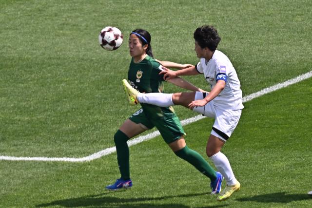North Korea's Naegohyang Women's FC forward Kim Kyong Yong (R) vies for the ball with  Japan's Tokyo Verdy Beleza defender Yuna Aoki during the AFC Women's Champions League final football match between North Korea's Naegohyang Women's FC and Japan's Tokyo Verdy Beleza at Suwon Sports Complex in Suwon on May 23, 2026. (Photo by Pedro Pardo / AFP)