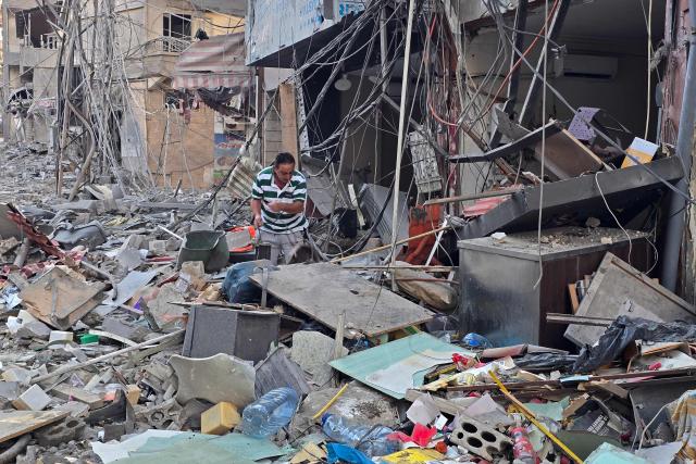 A man looks for his belongings amid debris of a destroyed building at the site of an Israeli strike in the southern Lebanese coastal city of Tyre on May 23, 2026. Two buildings in and around Tyre were struck overnight on May 22 into May 23, after the Israeli military issued an evacuation warning. (Photo by KAWNAT HAJU / AFP)