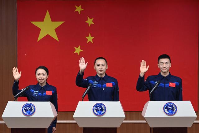 Astronauts for China's Shenzhou-23 space mission Lai Ka-ying (L), Zhu Yangzhu (C) and Zhang Zhiyuan (R) wave during a press conference before the launch of the mission at the Jiuquan Satellite Launch Center in the Gobi desert in Jiuquan, in northwestern China's Gansu province on May 23, 2026. (Photo by CNS / AFP) / China OUT