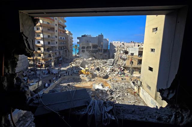 People inspect the site of an Israeli strike in the southern Lebanese coastal city of Tyre on May 23, 2026. Two buildings in and around Tyre were struck overnight on May 22 into May 23, after the Israeli military issued an evacuation warning. (Photo by KAWNAT HAJU / AFP)