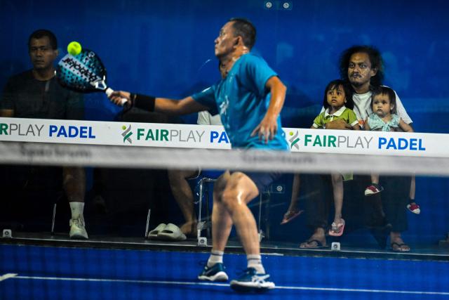 A man and his children watch a padel player compete during a padel exhibition tournament in Banda Aceh on May 23, 2026. (Photo by CHAIDEER MAHYUDDIN / AFP)