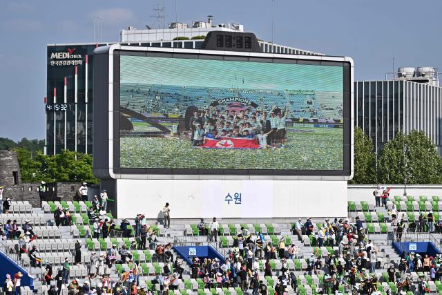 North Korea's Naegohyang Women's FC players are seen on a stadium screen celebrating with the trophy after defeating Japan's Tokyo Verdy Beleza in the AFC Women's Champions League final at Suwon Sports Complex in Suwon on May 23, 2026. (Photo by Pedro Pardo / AFP)