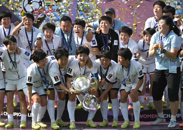 Naegohyang Women's FC players celebrate with the trophy during the victory ceremony after the AFC Women's Champions League final football match between North Korea's Naegohyang Women's FC and Japan's Tokyo Verdy Beleza in Suwon on May 23, 2026. (Photo by Jung Yeon-je / AFP)