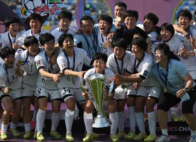 Naegohyang Women's FC players celebrate with the trophy during the victory ceremony after the AFC Women's Champions League final football match between North Korea's Naegohyang Women's FC and Japan's Tokyo Verdy Beleza in Suwon on May 23, 2026. (Photo by Jung Yeon-je / AFP)