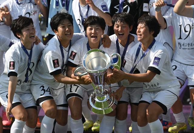 Naegohyang Women's FC players celebrate with the trophy during the victory ceremony after the AFC Women's Champions League final football match between North Korea's Naegohyang Women's FC and Japan's Tokyo Verdy Beleza in Suwon on May 23, 2026. (Photo by Jung Yeon-je / AFP)