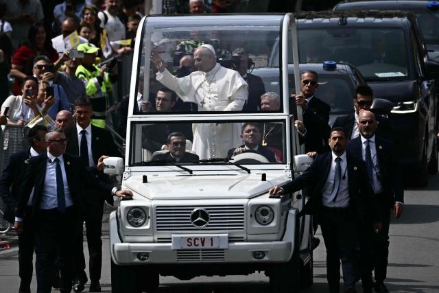 Pope Leo XIV waves to the crowd at Piazza Nicola Calipari during a pastoral visit to the community of the 'Land of Fires' on May 23, 2026. The Land of Fires (terra dei fuochi) is an area in the Southern Italian region of Campania were, systematically, since the end of the 80s, toxic wastes have been dumped by organized crime (Camorra) causing waste-related environmental crimes. Acerra and the surrounding territory has higher-than-average cancer rates, linked to the dumping, burning, and burying of toxic waste. (Photo by Filippo MONTEFORTE / AFP)