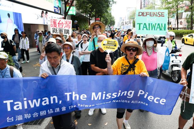 Protestors hold a banner and signs during a rally to oppose a scaled-down defence budget passed by the legislature in Taipei on May 23, 2026. The budget act removed five major military equipment items proposed in the Cabinet's proposed package. (Photo by I-Hwa Cheng / AFP)