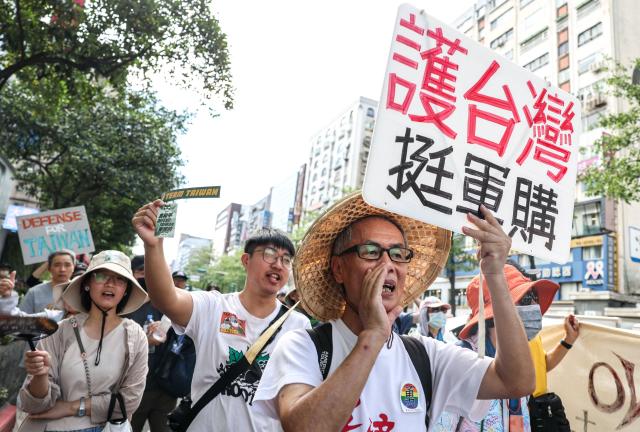 Protestors shout "Want peace, support arms purchases" during a rally to oppose a scaled-down defense budget passed by the legislature in Taipei on May 23, 2026. The budget act removed five major military equipment items proposed in the Cabinet's proposed package. (Photo by I-Hwa Cheng / AFP)