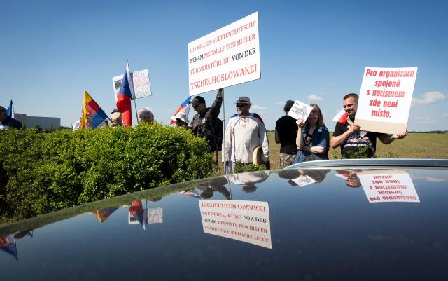 Protesters hold up posters to demonstrate against an event organised by the "Union of Expellees within the Christian Social Union party" (UdVA, Union der Vertriebenen, Aussiedler und Deutschen Minderheiten der CSU) to commemorate the flight and expulsion of Sudeten Germans during and after World War II, on May 23, 2026 in Pohorelice, South Moravia, Czech Republic. (Photo by Radek MICA / AFP)