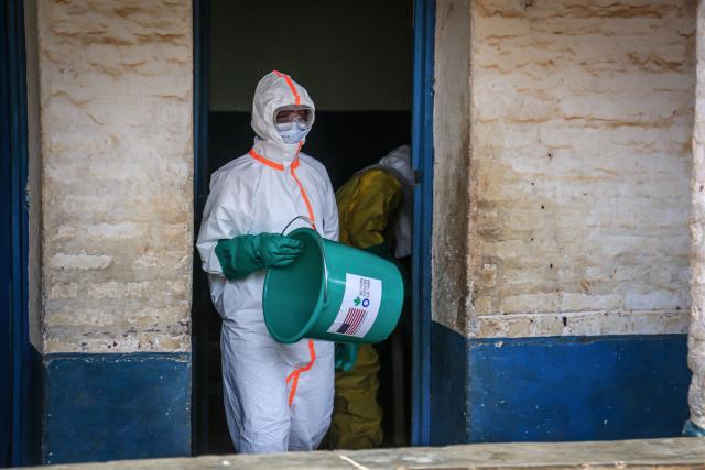 A health worker wearing protective equipment disinfects the isolation area for Ebola patients at the General Referral Hospital of Mongbwalu in Mongbwalu, on May 23, 2026. Ebola continues to spread in Democratic Republic of Congo, where the first cases of transmission were reported in the eastern province of South Kivu, while the health response is struggling to get organized and has given rise to scenes of chaos in Ituri province, the epicenter of the epidemic. The World Health Organization (WHO) issued an international health alert to address a 17th Ebola outbreak in the east of the Democratic Republic of Congo, a vast Central African country of more than 100 million inhabitants plagued by conflict. (Photo by Seros MUYISA / AFP)