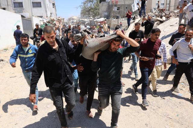 Palestinian mourners carry a body for burial from the al-Shifa Hospital past destroyed buildings in Gaza City on May 23, 2026, after Israeli airstrike targeted a police post in the Al-Tuam area, west of Jabalia in the northern Gaza Strip. An Israeli strike killed five police officers in the northern Gaza Strip on May 23, said a hospital and the Palestinian territory's police force, which operates under Hamas authority. A ceasefire has been in place since October 2025, but Israel reserves the right to strike targets it deems a threat. (Photo by Omar AL-QATTAA / AFP)