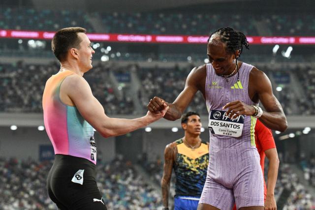 Winner Brazil's Alison Dos Santos (R) celebrates with second-placed Norway's Karsten Warholm at the end of the men's 400m hurdles final event during the Xiamen Diamond League athletics meeting at Egret Stadium in Xiamen, in China’s eastern Fujian province on May 23, 2026. (Photo by Hector RETAMAL / AFP)