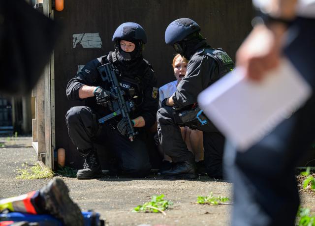 Police officers conduct a drill next to a woman playing the role of a victim during an emergency drill involving police, German Red Cross rescue workers and emergency responders, on May 23, 2026 in Bad Sobernheim, Rhineland-Palatinate, western Germany. (Photo by Hannes P. Albert / AFP)