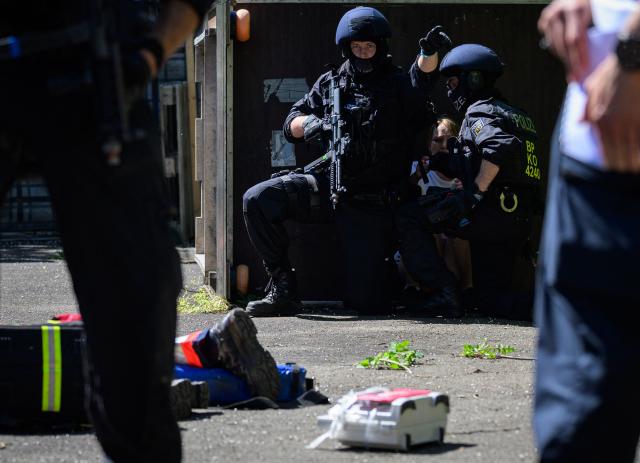 Police officers conduct a drill next to a woman playing the role of a civilian during a joint emergency drill involving police, German Red Cross rescue workers and emergency responders, on May 23, 2026 in Bad Sobernheim, Rhineland-Palatinate, western Germany. (Photo by Hannes P. Albert / AFP)