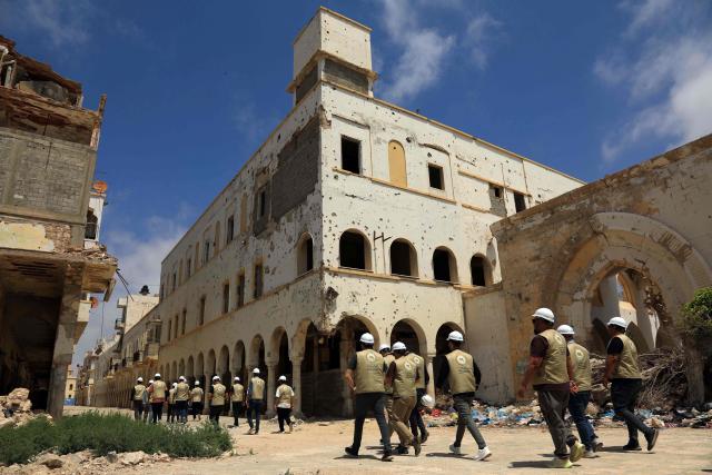 Engineers walk past damaged buildings during the reconstruction of the historical centre, partially destroyed during the country's civil war, in the Old City of Benghazi, situated in eastern Libya along the Mediterranean coast, on May 23, 2026. Libya remains plagued by division and instability after years of unrest following the NATO-backed uprising that toppled longtime leader Muammar Gaddafi in 2011. Libya is still divided between the UN-recognised government in the west and its eastern rival in the east, backed by military commander Khalifa Haftar. (Photo by Abdullah DOMA / AFP)
