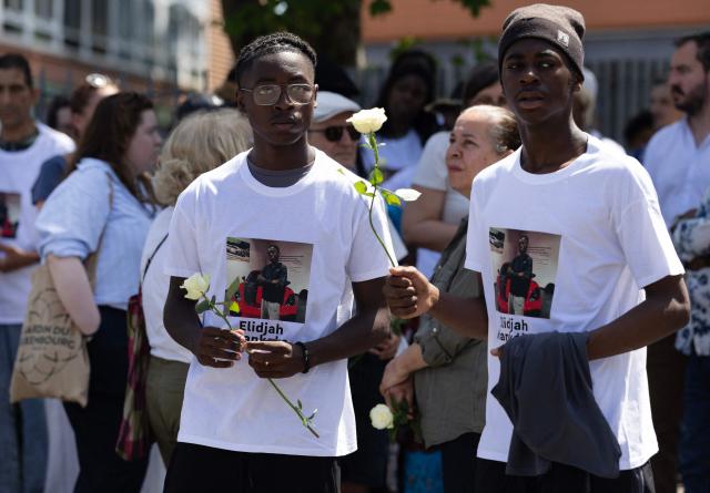 Relatives hold flowers as they take part in a silent march in tribute to Elidjah Mankoka in Nantes, western France on May 23, 2026, after his death by shooting on May 14. The death of fifteen year-old Elidjah along with the wounding of two other minors on the same day, took place in the Port-Boyer neighbourhood on the western French city, which had already been hit by deadly shootings linked to drug trafficking earlier in the year. (Photo by Fred TANNEAU / AFP)