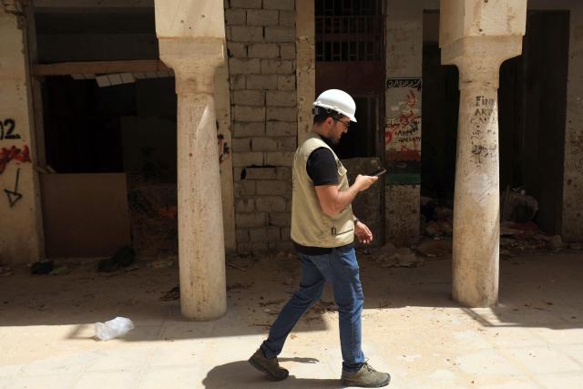 An engineer looks at his mobile phone as he walks past a covered walk way during the reconstruction of the historical centre, partially destroyed during the country's civil war (2014-2017), in the Old City of Benghazi, situated in eastern Libya along the Mediterranean coast, on May 23, 2026. Libya remains plagued by division and instability after years of unrest following the NATO-backed uprising that toppled longtime leader Muammar Gaddafi in 2011. Libya is still divided between the UN-recognised government in the west and its eastern rival in the east, backed by military commander Khalifa Haftar. (Photo by Abdullah DOMA / AFP)