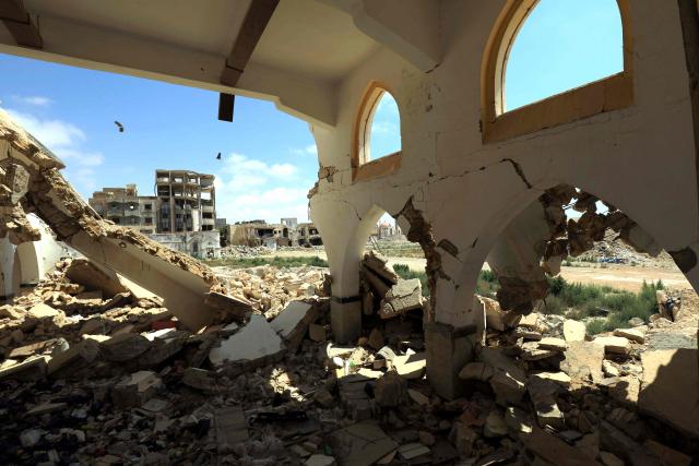Birds fly over damaged buildings in the historical centre, partially destroyed during the country's civil war, in the Old City of Benghazi, situated in eastern Libya along the Mediterranean coast, on May 23, 2026. Libya remains plagued by division and instability after years of unrest following the NATO-backed uprising that toppled longtime leader Muammar Gaddafi in 2011. Libya is still divided between the UN-recognised government in the west and its eastern rival in the east, backed by military commander Khalifa Haftar. (Photo by Abdullah DOMA / AFP)