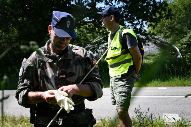 A French gendarme officer put gloves as volunteers participate in a community search in Saint-Étienne-de-Montluc, western France on May 23, 2026, as they look for information relating to Manon Relandeau, who has been missing since March 27. Some 300 volunteers combed the area on the outskirts of Nantes in an effort to find clues relating to the 31-year-old farmer who has been missing for nearly two months. (Photo by Lou BENOIST / AFP)