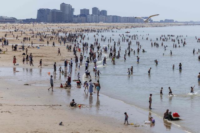Beachgoers stand an the shoreline of the Belgian North Sea coast during a hot day in Ostend on May 23, 2026. Tourists are expected to flock the Belgian coast, as temperatures are rising for the weekend. (Photo by NICOLAS MAETERLINCK / Belga / AFP) / Belgium OUT