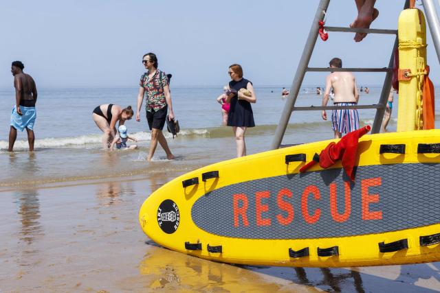 A photo shows a lifeguard's board as beachgoers walk along the shoreline of the Belgian North Sea coast during a hot day in Ostend on May 23, 2026. Tourists are expected to flock the Belgian coast, as temperatures are rising for the weekend. (Photo by NICOLAS MAETERLINCK / Belga / AFP) / Belgium OUT