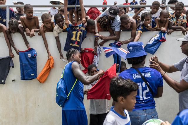 Supporters wait to have their t-shirts signed by Cape Verde’s defender Sidny Lopes Cabral (C) at the end of a training session to prepare for their participation in the 2026 FIFA World Cup at Estadio Municipal 25 de Julho in Santa Cruz, on May 23, 2026. (Photo by PATRICK MEINHARDT / AFP)