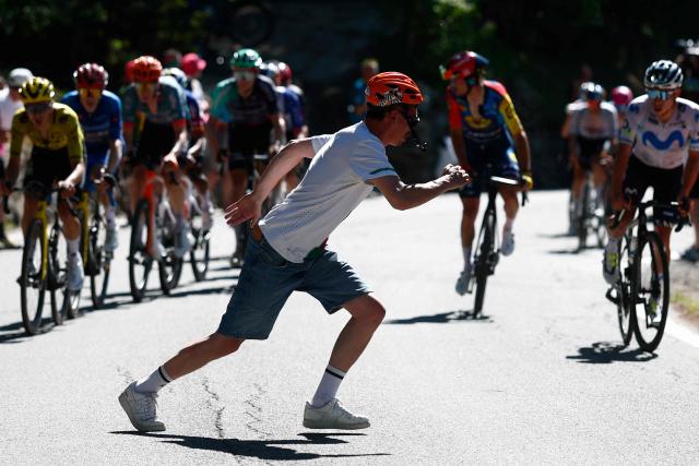 A man crosses the road in front of riders during a climb in the 14th stage of the Giro d'Italia 2026 - Tour of Italy cycling race between Aosta and Pila (Gressan), Italy, on May 23, 2026. (Photo by Luca Bettini / AFP)
