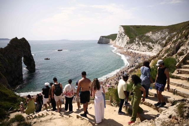 People use the steps down onto Durdle Door beach, east of Weymouth on the south coast of England on May 23, 2026, as temperatures are set to rise over the long bank holiday weekend. (Photo by Henry NICHOLLS / AFP)
