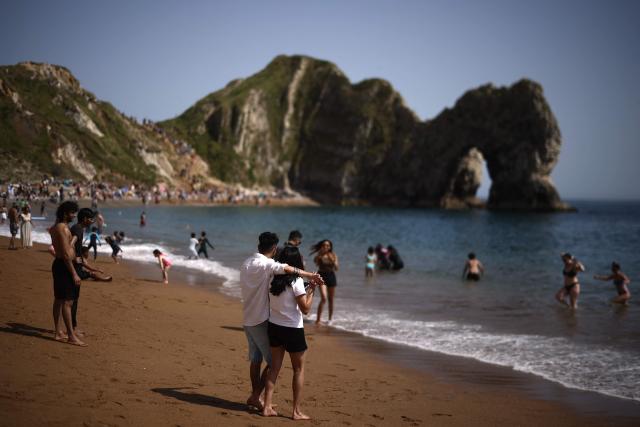 People relax in the sunshine on Durdle Door beach, east of Weymouth on the south coast of England on May 23, 2026, as temperatures are set to rise over the long bank holiday weekend. (Photo by Henry NICHOLLS / AFP)