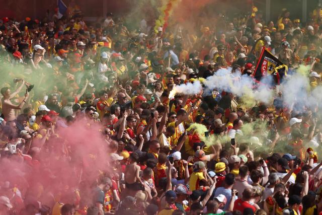 RC Lens supporters wave flags and burn flares as they gather on the Place Jean-Jaures during celebrations following the club's victory in the French Cup final football match against OGC Nice, in Lens, northern France on May 23, 2026. (Photo by FRANCK FIFE / AFP)
