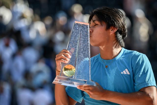 US's Learner Tien celebrates with the winner's trophy after winning the ATP 250 Geneva Open tennis tournament men's singles final match against Argentine's Mariano Navone in Geneva on May 23, 2026. (Photo by Fabrice COFFRINI / AFP)