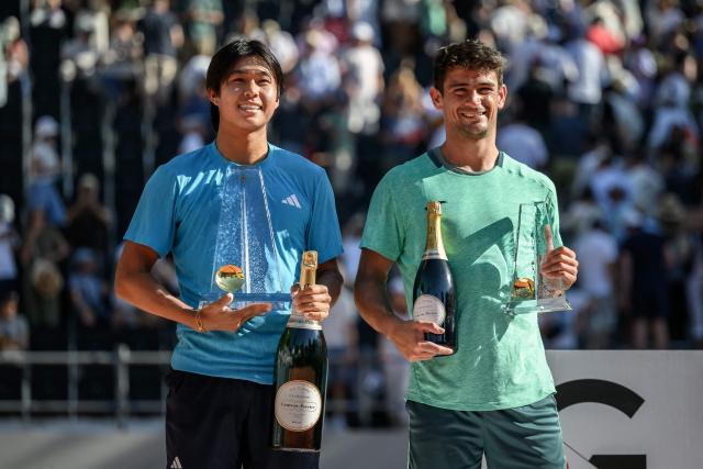 US' Learner Tien (L) poses with the winner's trophy after winning the ATP 250 Geneva Open tennis tournament men's singles final match next to his runner-up Argentine's Mariano Navone in Geneva on May 23, 2026. (Photo by Fabrice COFFRINI / AFP)