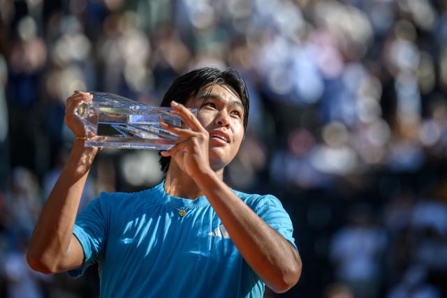 US' Learner Tien raises the winner's trophy after winning the ATP 250 Geneva Open tennis tournament men's singles final match against Argentine's Mariano Navone in Geneva on May 23, 2026. (Photo by Fabrice COFFRINI / AFP)
