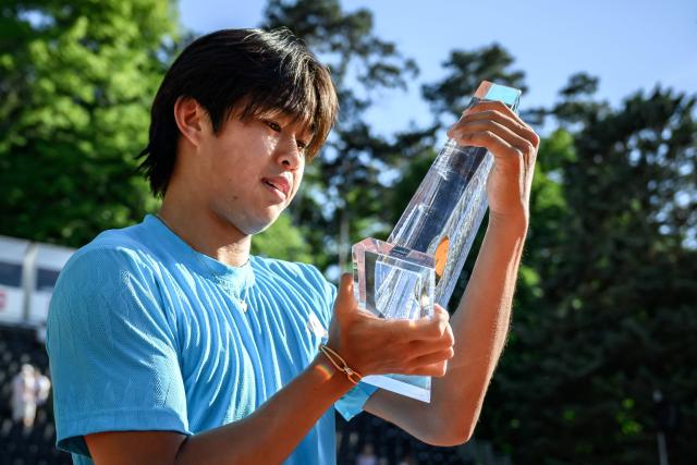 US' Learner Tien holds the winner's trophy after winning the ATP 250 Geneva Open tennis tournament men's singles final match against Argentine's Mariano Navone in Geneva on May 23, 2026. (Photo by Fabrice COFFRINI / AFP)