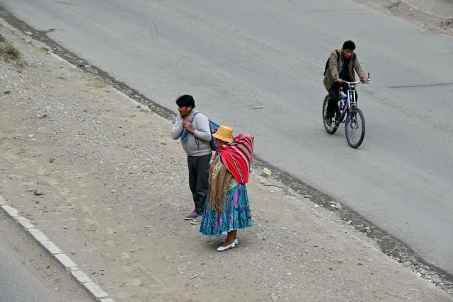 People ride and walk past roadblocks against the government of Bolivian President Rodrigo Paz, in El Alto, Bolivia, on May 23, 2026. The Bolivian government said it would deploy a police and military operation starting on the morning of May 23 to allow the passage of scarce goods into La Paz through roadblocks, as unions and Indigenous groups press their calls for President Rodrigo Paz to step down. (Photo by AIZAR RALDES / AFP)