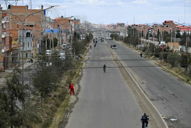 People ride and walk past roadblocks against the government of Bolivian President Rodrigo Paz, in El Alto, Bolivia, on May 23, 2026. The Bolivian government said it would deploy a police and military operation starting on the morning of May 23 to allow the passage of scarce goods into La Paz through roadblocks, as unions and Indigenous groups press their calls for President Rodrigo Paz to step down. (Photo by AIZAR RALDES / AFP)