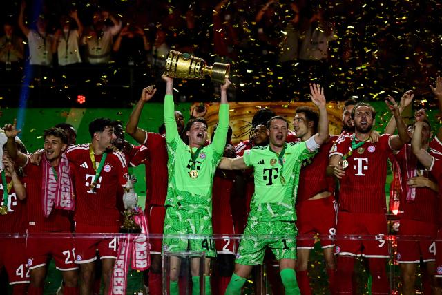 Bayern Munich players celebrate with the trophy after the German Cup (DFB Pokal) final football match FC Bayern Munich v VfB Stuttgart at the Olympic Stadium in Berlin, on May 23, 2026. (Photo by Tobias SCHWARZ / AFP) / DFB REGULATIONS PROHIBIT ANY USE OF PHOTOGRAPHS AS IMAGE SEQUENCES AND QUASI-VIDEO.
