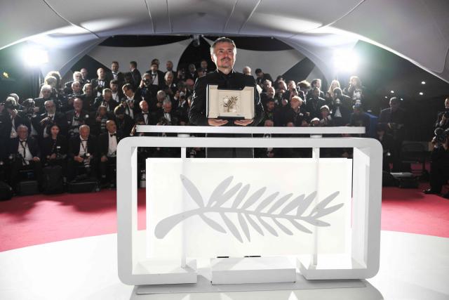 Romanian director, screenwriter and producer Cristian Mungiu poses with the trophy during a photocall after winning the Palme d'Or for the film "Fjord" during the closing ceremony of the 79th edition of the Cannes Film Festival in Cannes, southern France, on May 23, 2026. (Photo by Olivier CHASSIGNOLE / AFP)