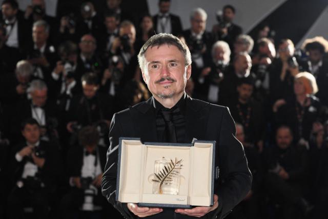 Romanian director, screenwriter and producer Cristian Mungiu poses with the trophy during a photocall after winning the Palme d'Or for the film "Fjord" during the closing ceremony of the 79th edition of the Cannes Film Festival in Cannes, southern France, on May 23, 2026. (Photo by Olivier CHASSIGNOLE / AFP)