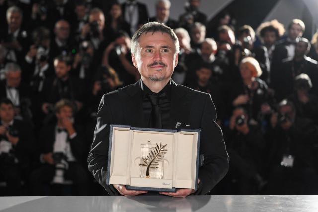 Romanian director, screenwriter and producer Cristian Mungiu poses with the trophy during a photocall after winning the Palme d'Or for the film "Fjord" during the closing ceremony of the 79th edition of the Cannes Film Festival in Cannes, southern France, on May 23, 2026. (Photo by Olivier CHASSIGNOLE / AFP)