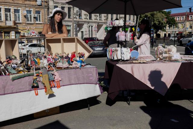 A woman stands behind her stall at a street market in Kyiv on May 23, 2026, amid the Russian invasion of Ukraine. (Photo by Tetiana DZHAFAROVA / AFP)