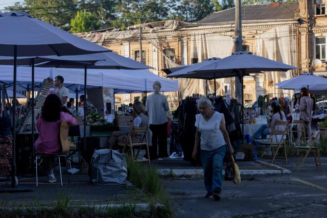 A woman walks down the street near the street market in Kyiv on May 23, 2026, amid the Russian invasion of Ukraine. (Photo by Tetiana DZHAFAROVA / AFP)