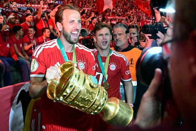 Bayern Munich's English forward #09 Harry Kane and his teammates celebrate with the trophy in front of their fans after the German Cup (DFB Pokal) final football match FC Bayern Munich v VfB Stuttgart at the Olympic Stadium in Berlin, on May 23, 2026. (Photo by Tobias SCHWARZ / AFP) / ALTERNATIVE CROP